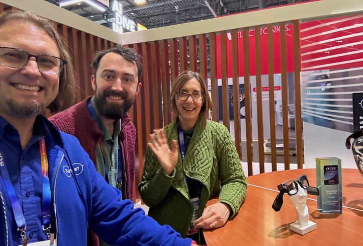 Three people standing beside an exhibit table, posing for camera