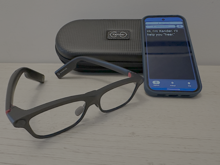 smart glasses with case and handheld captioning device on table